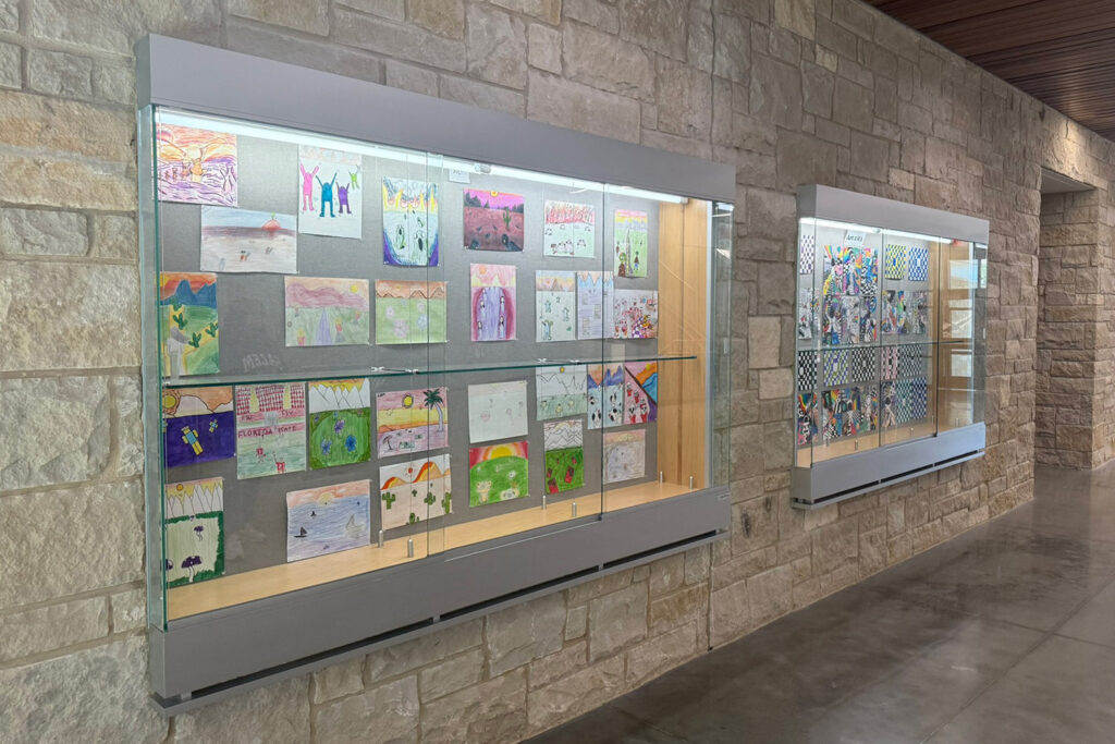 Glass display cases with student art on stone wall