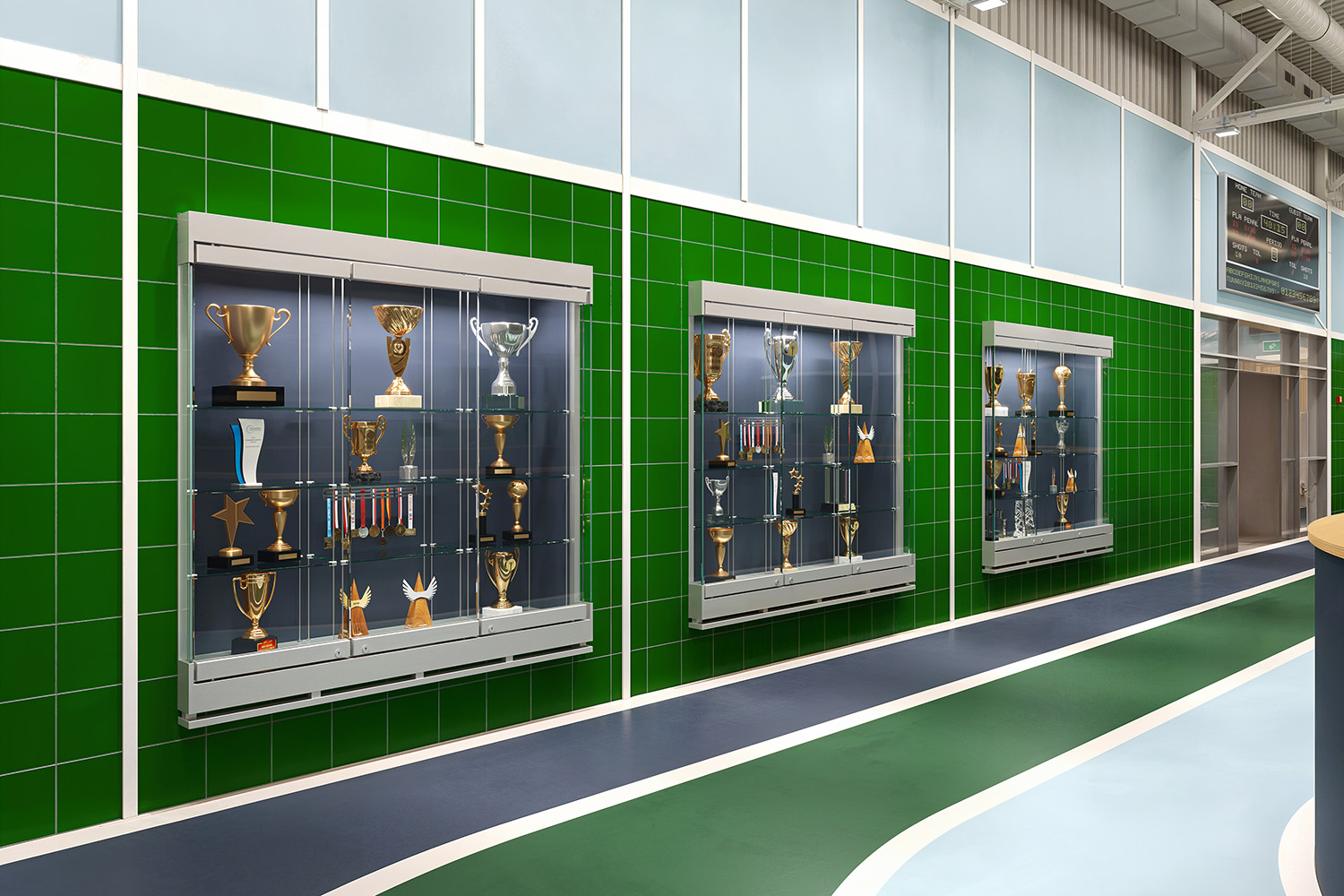 Glass display cases holding trophies on green tiled wall